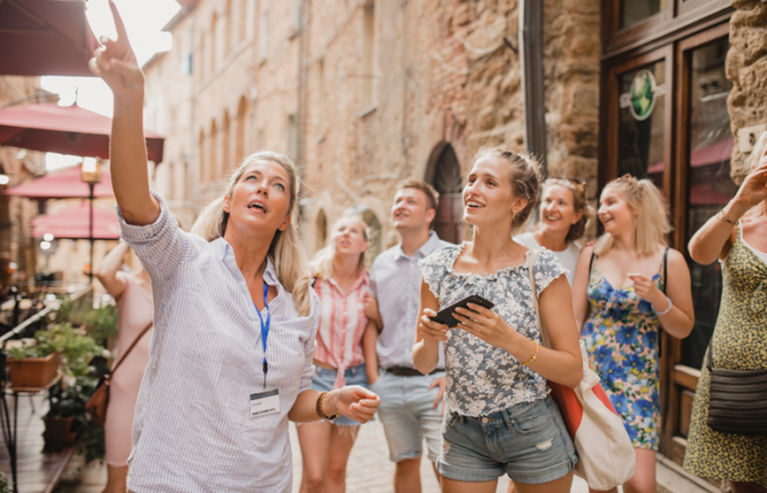 A group of people taking photos in a historic town, surrounded by old buildings and cobblestone streets.