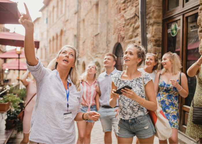 A group of people taking photos in a historic town, surrounded by old buildings and cobblestone streets.